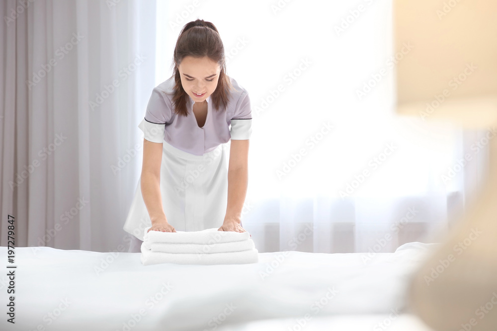 Sticker young maid with stack of towels in hotel room