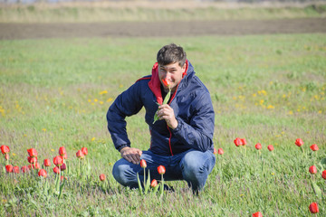 Fototapeta premium A man in a jacket on a field of tulips. Glade with tulips