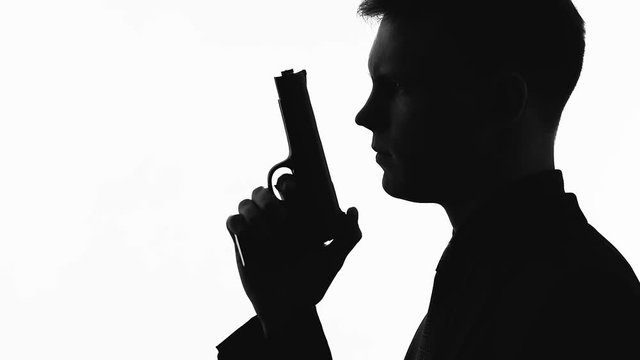 Silhouette of male serial killer holding gun, preparing to shoot, crime and law