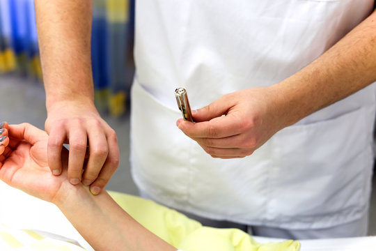 Pfleger misst den Puls einer jungen Patientin am Handgelenk in einem Krankenzimmer / Selektiver Fokus