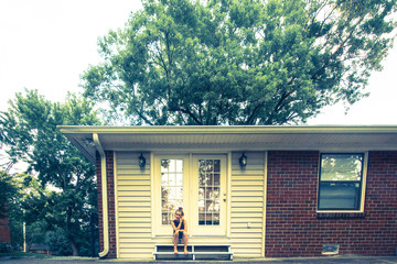 young woman sitting on front porch steps