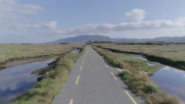 Aerial Footage Of Road Amidst Grassy Landscape Against Sky