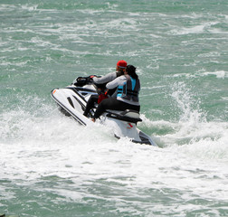 Obraz premium Young afro-american couple riding tandem on a jet. ski on the florida intra-coastal waterway off Miami Beach.