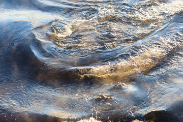 Water vapor on surface of cold icy water at sunny cold winter day