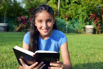 beautiful and happy girl reading bible outdoors