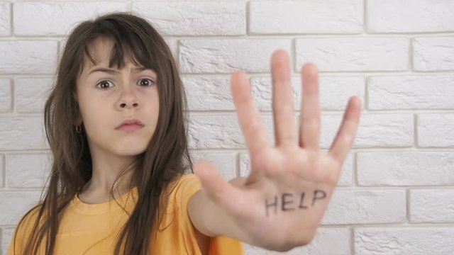 Child abuse. Domestic violence. A frightened child asks for help. A little girl shows an inscription on the palm of HELP.