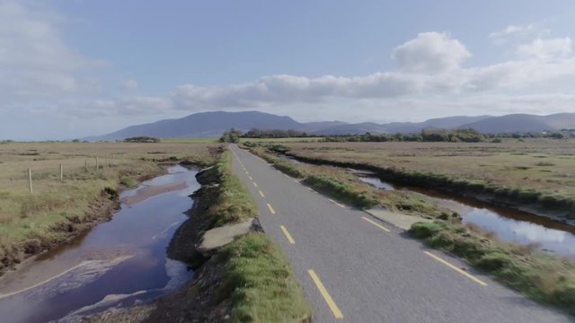 Aerial Footage Of Road Amidst Green Field With Water