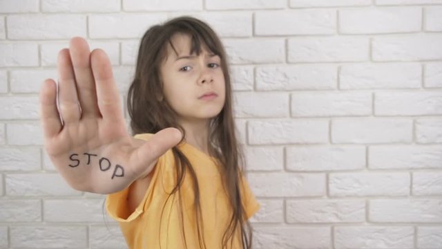 Child abuse. Domestic violence. A little girl shows an inscription on the hand of STOP.