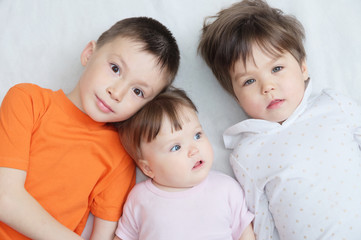 happy kids, three children different ages lying, portrait of boy, little girl and baby girl, happiness in childhood of siblings, living in big family with three children