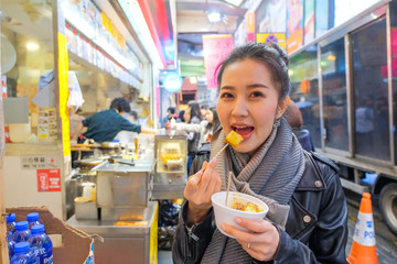 Asian young woman eating Chinese steamed dumpling street food in Hong Kong