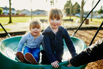 Fototapeta na wymiar two young sisters playing on swing