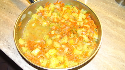 Zucchini stewed with carrots and onions in a pan.