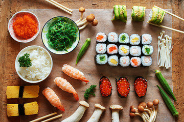 Assorted sushi, bowl of rice, tobiko, mushroom and okra on wooden table. Traditional japanese meal. 