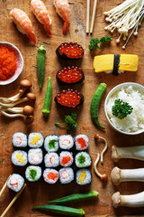 Assorted sushi, bowl of rice, tobiko, mushroom and okra on wooden table. Traditional japanese meal. 