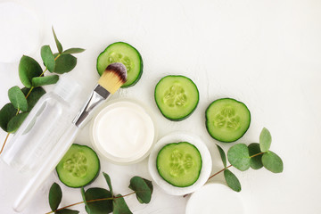 Cucumber slices, cosmetic cream jar and tonic mineral water in bottle, fresh green eucalyptus...