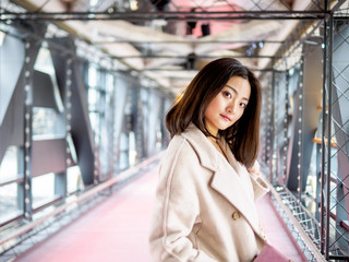 Portrait of beautiful young Chinese woman wearing beige coat posing in Shanghai Xintiandi, she smiling on gray brick background, happy time , Asian girl Concept, shopping Concept.