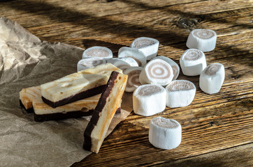 Marshmallow carelessly lying on a wooden table, lit by the rays of the warm sun.