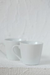 Obraz na płótnie Canvas tableware mockup. Minimalist cup Mockup. Two white cups on a white relief background. White cup . copy space