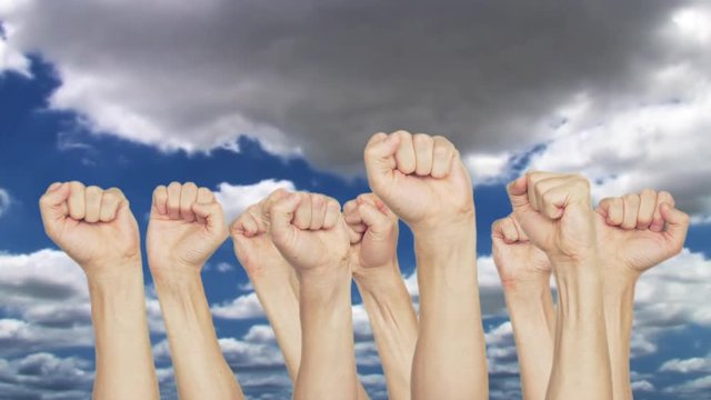 People by turns raising up clenched fist on blue sky background