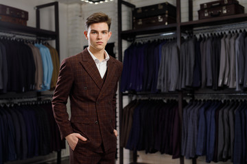 Fototapeta na wymiar young man in classic vest against row of suits in shop