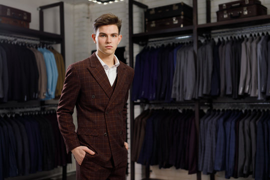 young man in classic vest against row of suits in shop