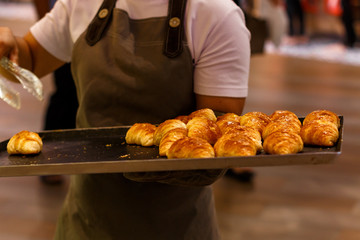 The seller of buns walking around the store with a tray and serves freshly baked pastries