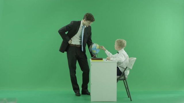 a teacher and his pupil looking at globe on green screen