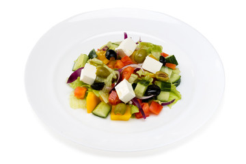 Greek salad in a white plate on a white background