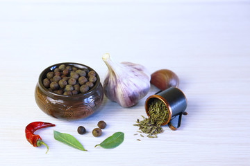 Background with aromatic spices. Seed of sweet-scented pepper in a ceramic pot, garlic, bay leaf, chili and sprinkled cumin.