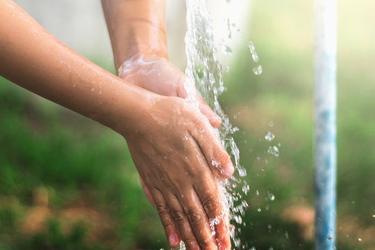 water pouring in faucet  on hand child for cleaning in park