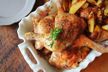Grilled chicken leg with potato for garnish. Top view. Wooden background.