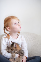 A girl with two pigtails and a cat in her arms