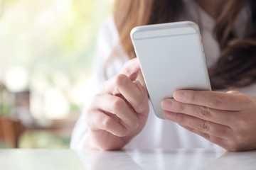 Closeup image of a woman holding , using and looking at smart phone