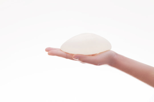Silicone breast implant on hands .