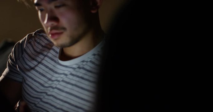 4K Young man relaxing at home late at night, browsing the internet on digital tablet