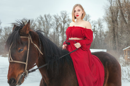 Woman in a red dress riding a horse.