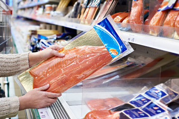 Vrouw koopt lichtgezouten rode vis in winkel