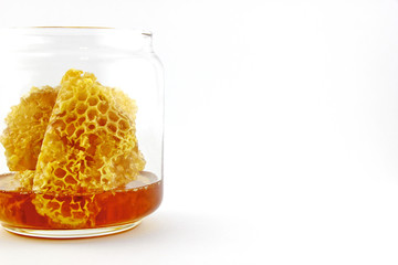 Fresh honey with honeycomb in glass jar on a white background
