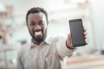 Innovative smartphone. Selective focus of a modern smartphone being in hands of a nice positive delighted man
