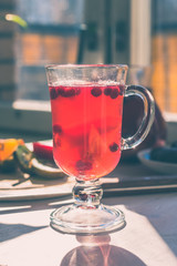 A glass with a cranberry drink on a rustic table, lit by the morning sun - the concept of a healthy life