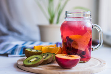 Iced red fruit tea in a glass and fresh tropical fruits on a wooden tray