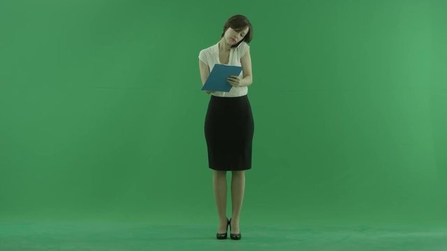 A business woman talking on her phone and writes something on the green screen