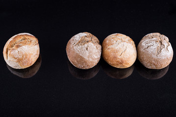 Freshly baked homemade artisan breads on black glossy table