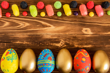 Easter conceptual photo with eggs and color cendy on wooden background