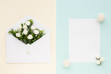 Workspace. Wedding invitation card, envelope, white roses and green leaves on beige blue background. Overhead view. Flat lay, top view wedding invitation card Templates.