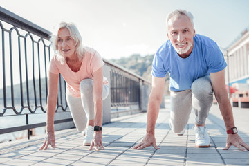 Who will win. Confident friendly aged couple preparing to run across the quay looking straight and...