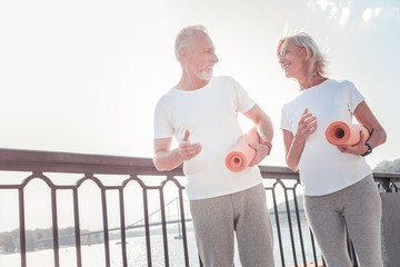 Lets do it together. Senior cute sporting couple communicating going across the quay and holding...