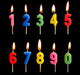 Burning candles in the form of figures (numbers, dates) for cake isolated on black background. The...