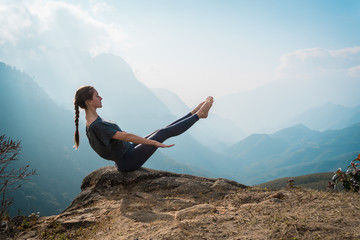 Woman training yoga on mountain cliff