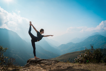Woman training yoga, mountains on background - obrazy, fototapety, plakaty